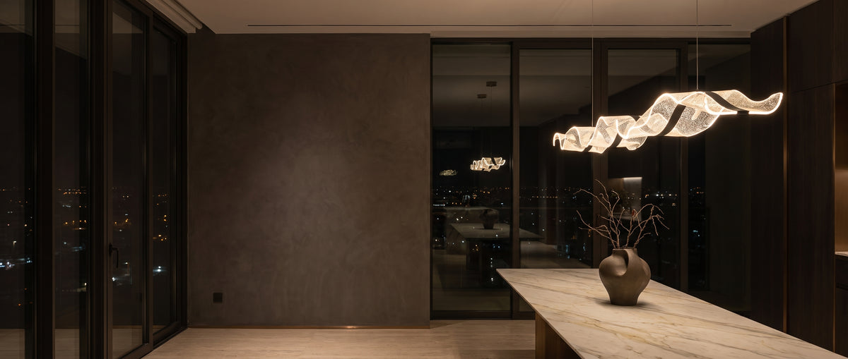 Wavy sculpted LED pendant light glowing over a marble dining table